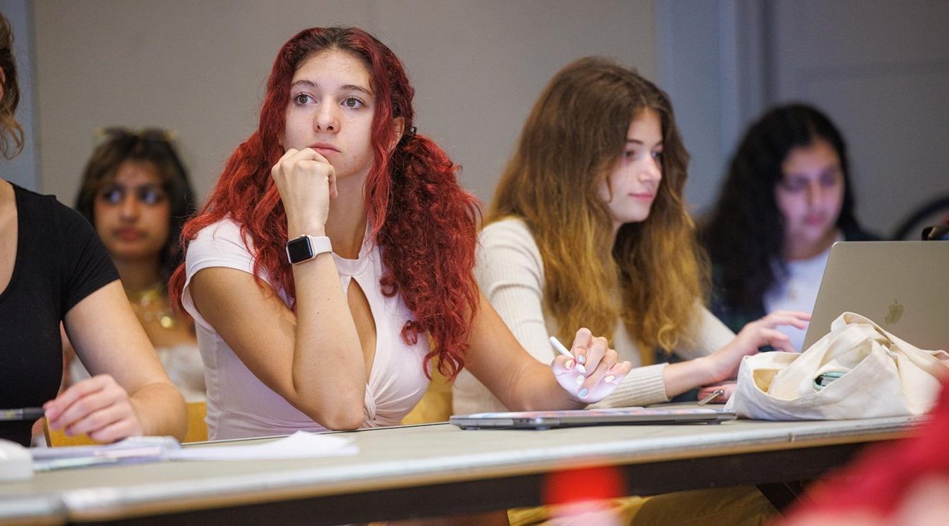 a student with bright red hair sits in a classroom